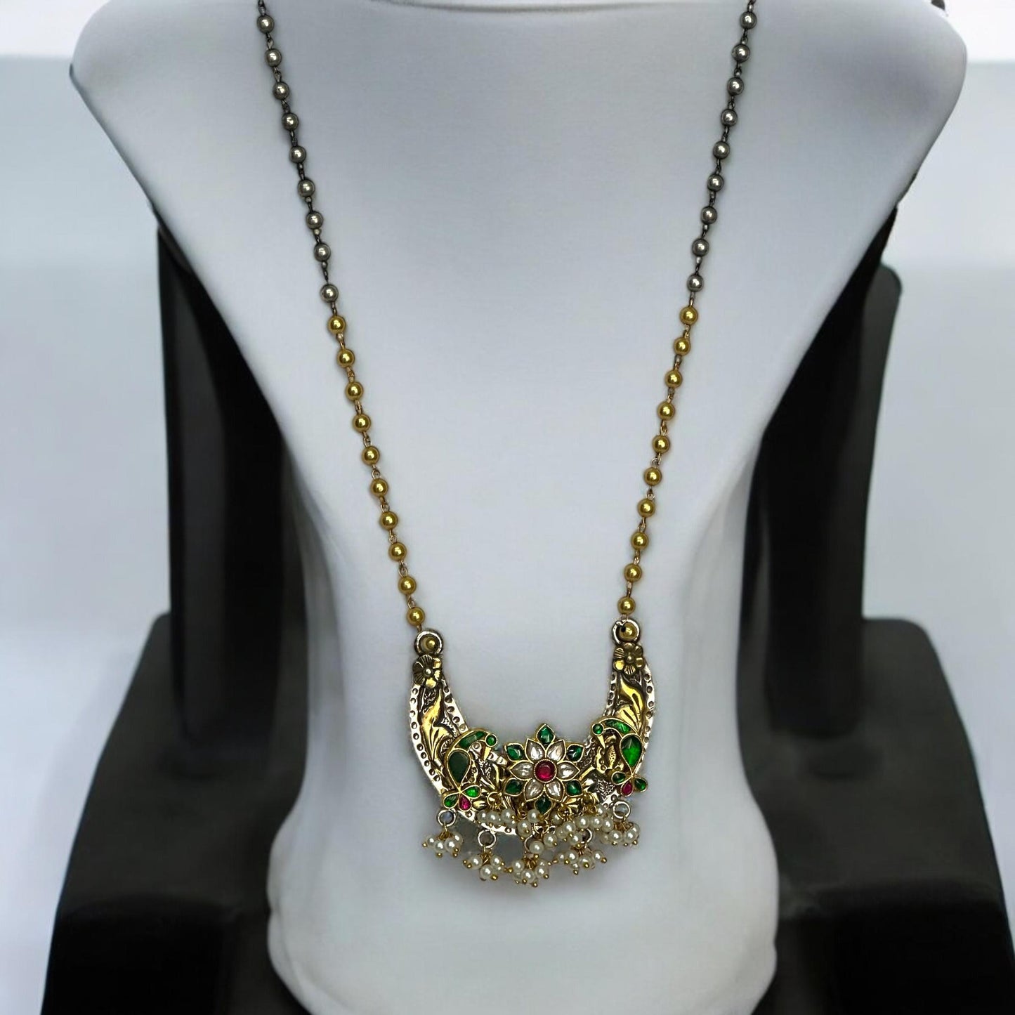 Jadau Pachi Kundan pendant in a fusion design with floral detailing, suspended from a long Amrapali dual-tone chain, displayed on a white mannequin.
