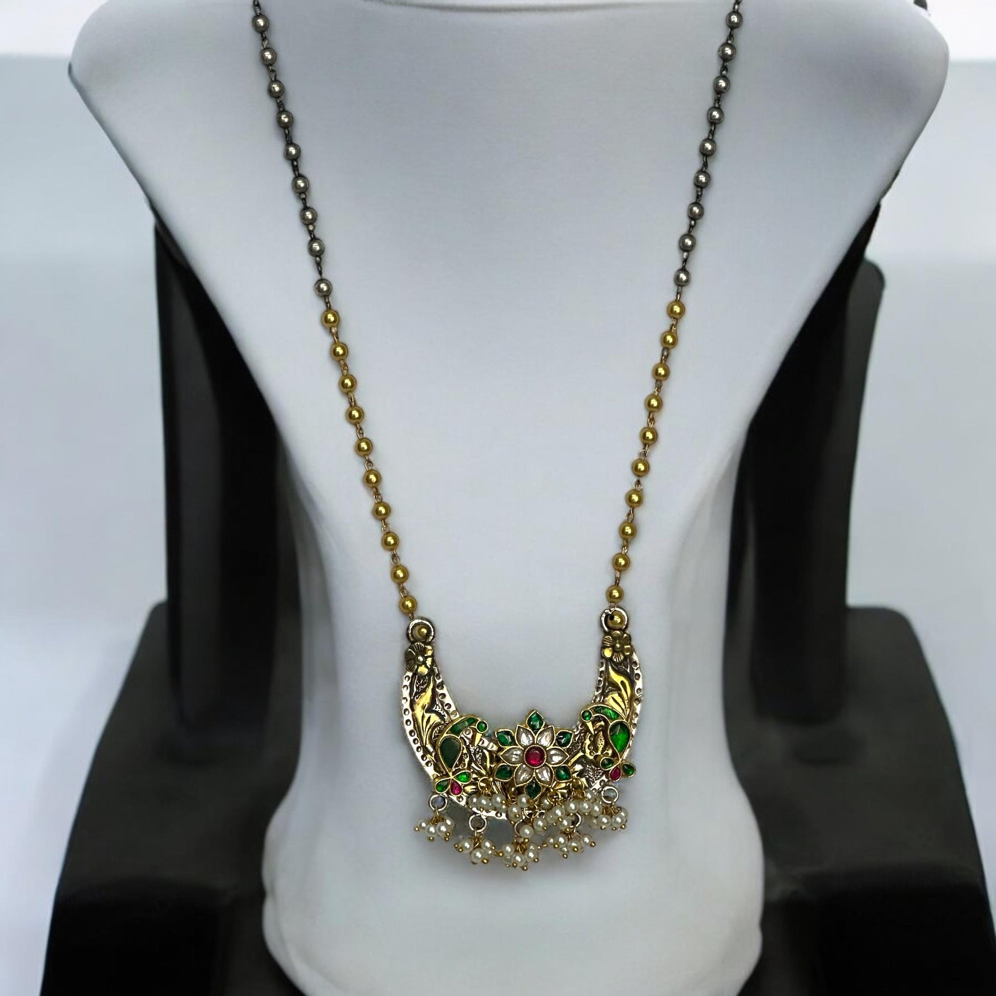 Jadau Pachi Kundan pendant in a fusion design with floral detailing, suspended from a long Amrapali dual-tone chain, displayed on a white mannequin.