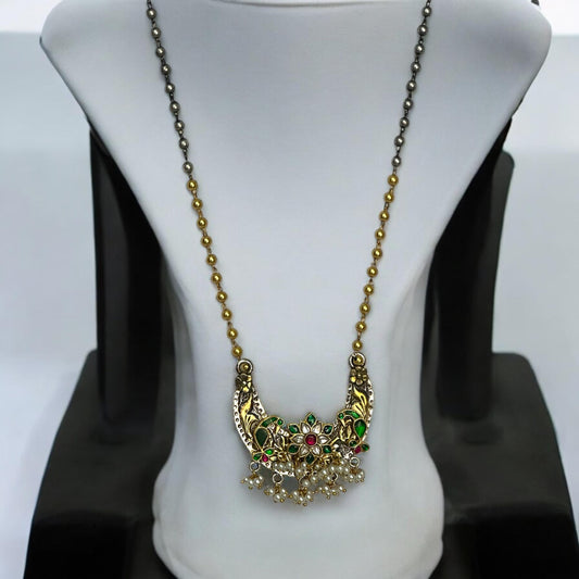 Jadau Pachi Kundan pendant in a fusion design with floral detailing, suspended from a long Amrapali dual-tone chain, displayed on a white mannequin.