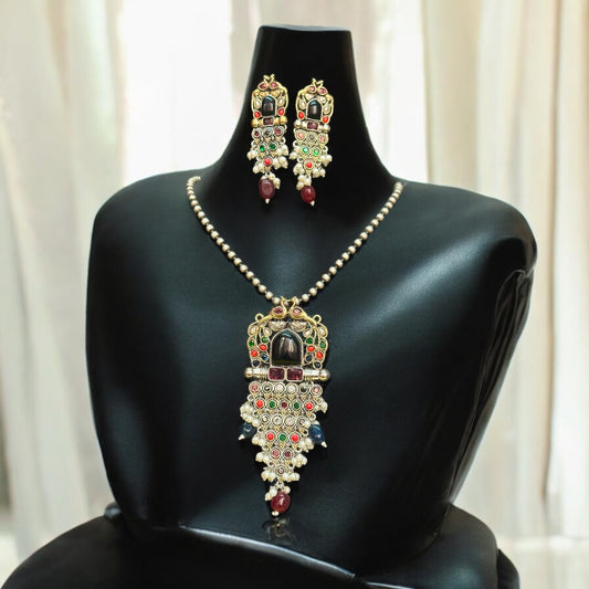 Long silver dual-tone peacock pendant set with intricate detailing, adorned with multicolor stones, pearls, and a matching pair of earrings, displayed against a soft beige curtain background.