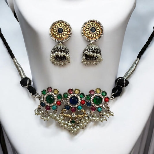 Minimal silver dual-tone choker necklace adorned with multicolor gemstones and pearl detailing, paired with intricate jhumki earrings, displayed on a white mannequin background.