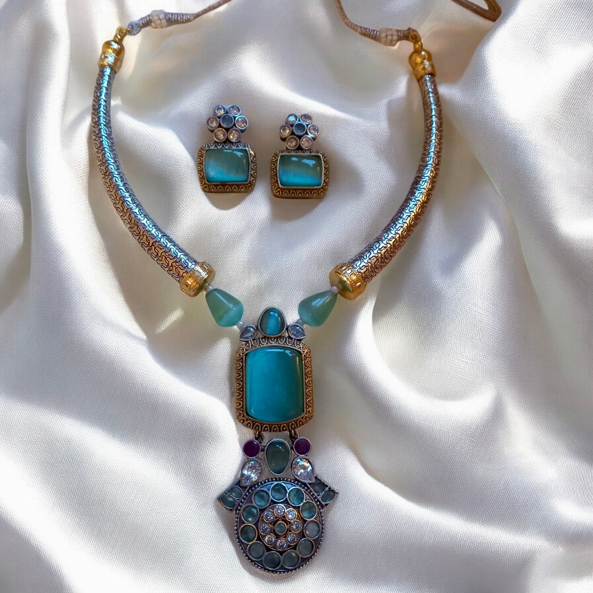 Mint green Monalisa stone Hasli-style German silver necklace set with matching earrings on white fabric  background