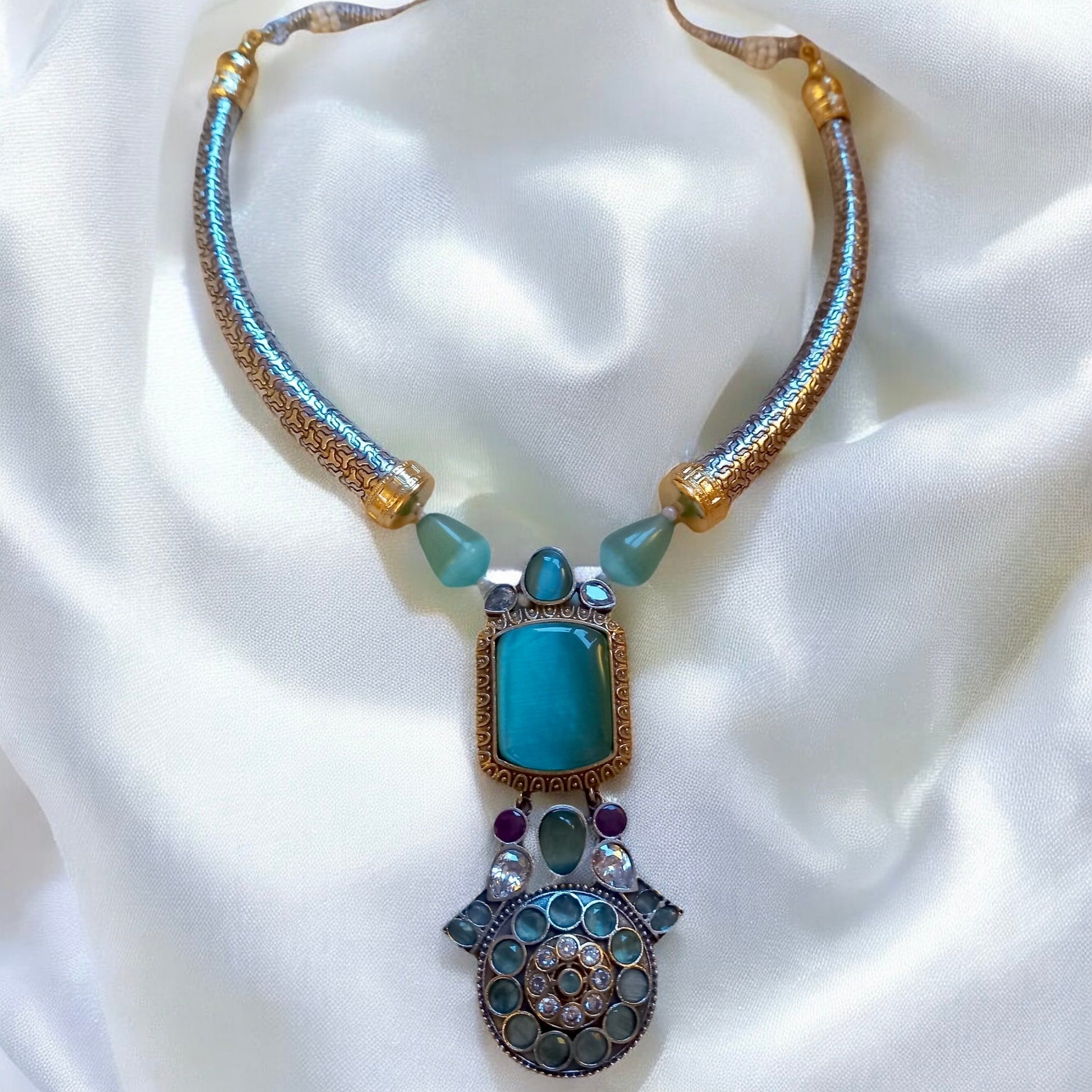 Mint green Monalisa stone Hasli-style German silver necklace with matching earrings on white fabric  background