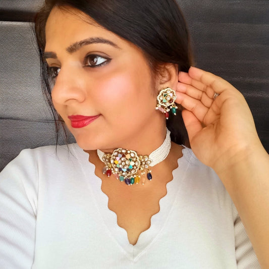 A model wearing and displaying side view of a Moissanite Multi-Color Choker Necklace with Earrings set– floral centerpiece with multi-colored enamel, pearl strands, and colorful bead drops. Perfect for festive and cultural occasions.