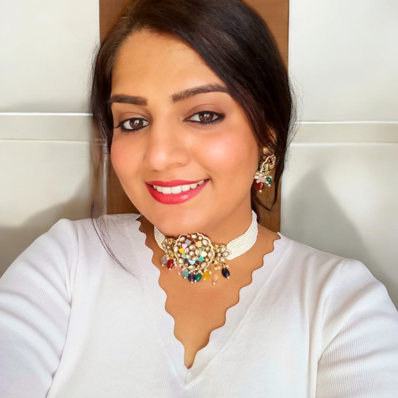 A model displaying a Moissanite Multi-Color Choker Necklace with Earrings set– floral centerpiece with multi-colored enamel, pearl strands, and colorful bead drops. Perfect for festive and cultural occasions.