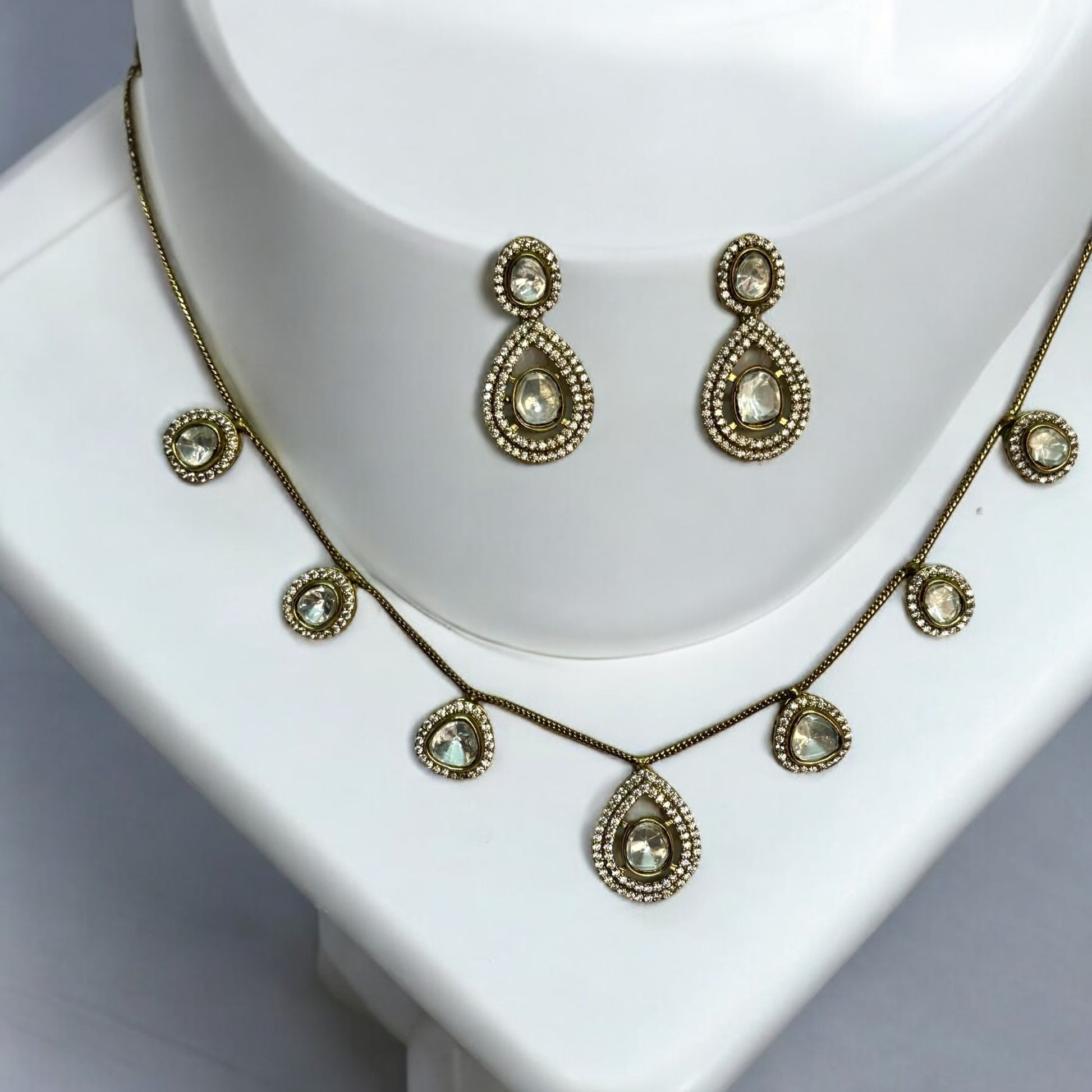 Moissanite chain design necklace set with earrings in golden colour places on a white colored jewellery display stand.