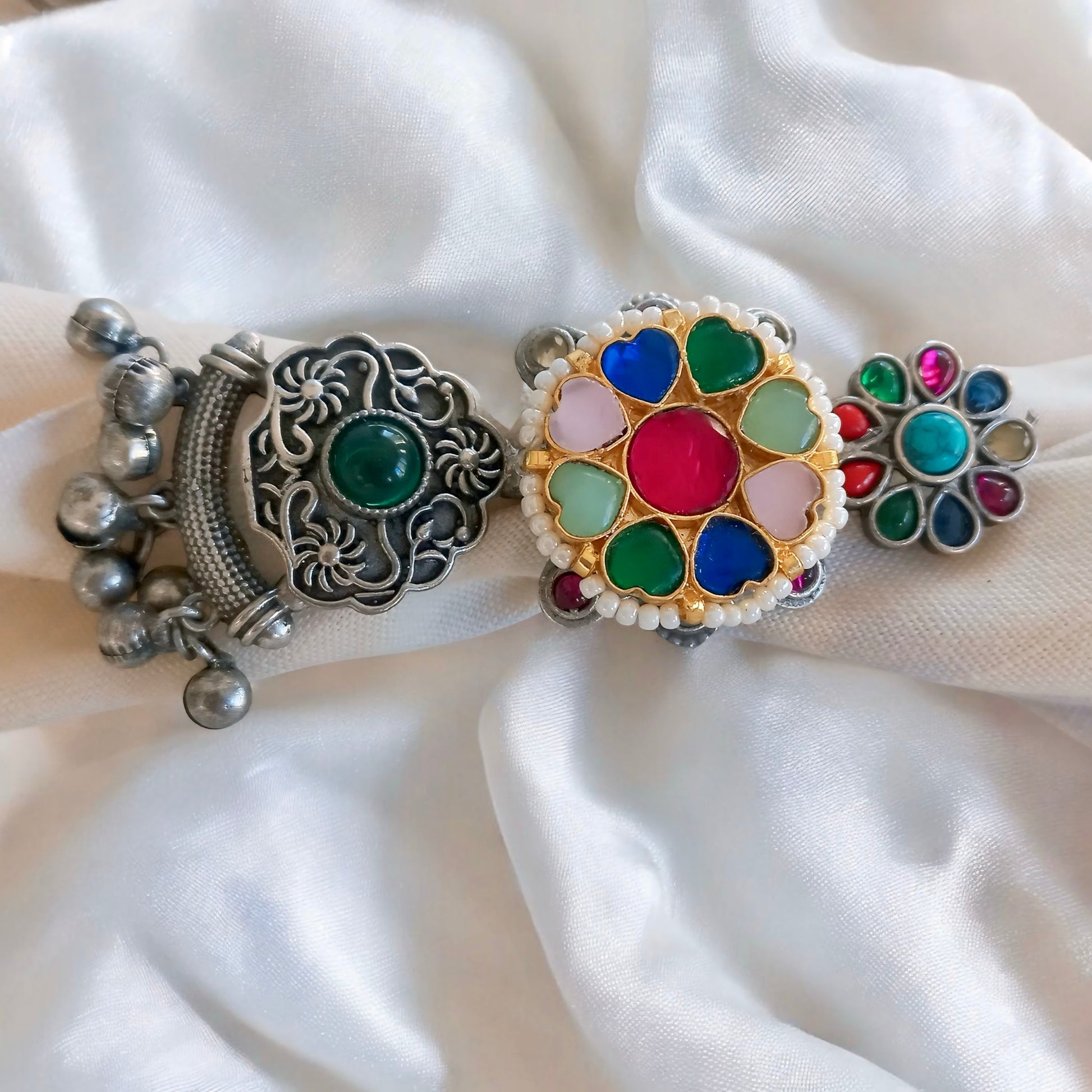 A white fabric background with a Multicolor Fusion Ring, featuring an intricate long adjustable design with colorful gemstones, complementing an ethnic-inspired look.