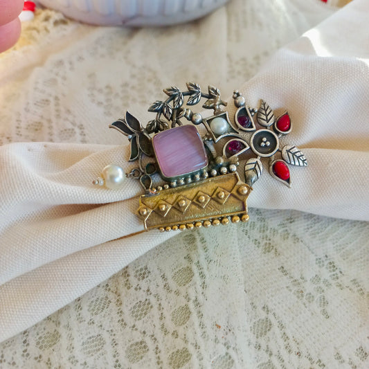 A white fabric backgroundwith an Oxidised Adjustable Fusion Ring, featuring intricate floral motifs, pearls, and a fusion of silver and gold-tone textures, perfect for a bold ethnic statement.