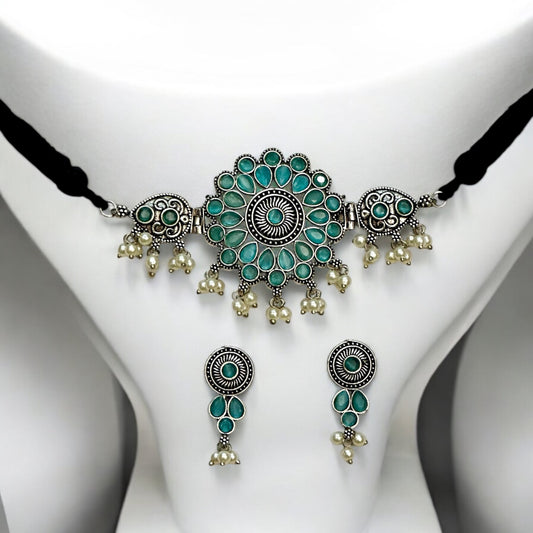 Oxidized silver choker necklace with intricate sky-blue floral designs and pearl drops. Includes matching earrings with coordinated patterns, set on a white bust display.