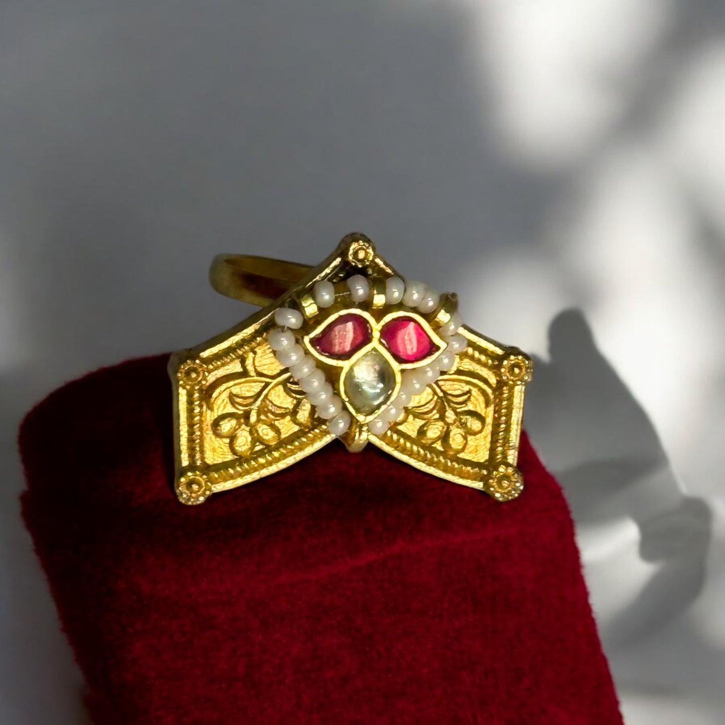 Traditional Pachi Kundan ring in gold-tone with intricate design, adorned with red and white gemstones and delicate pearl detailing.