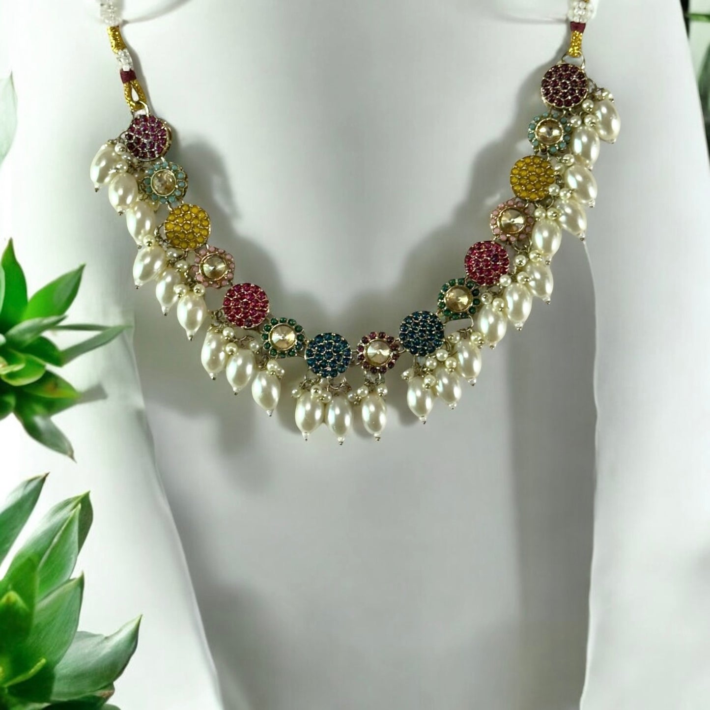 Pakistani Kundan Choker Necklace decorated on a white colored jewellery display stand with a few plant leaves on corners.