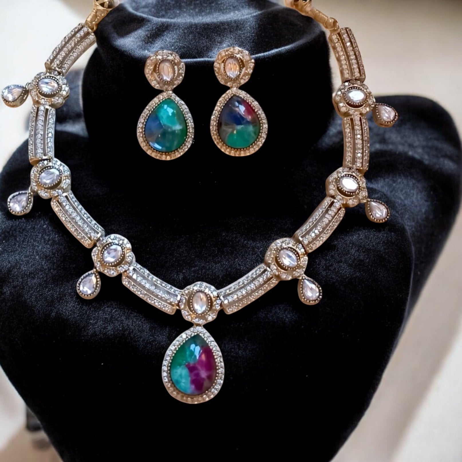 Premium moissanite necklace set with green and ruby multi-colour doublet stones and matching earrings, placed on a black velvet jewellery display stand