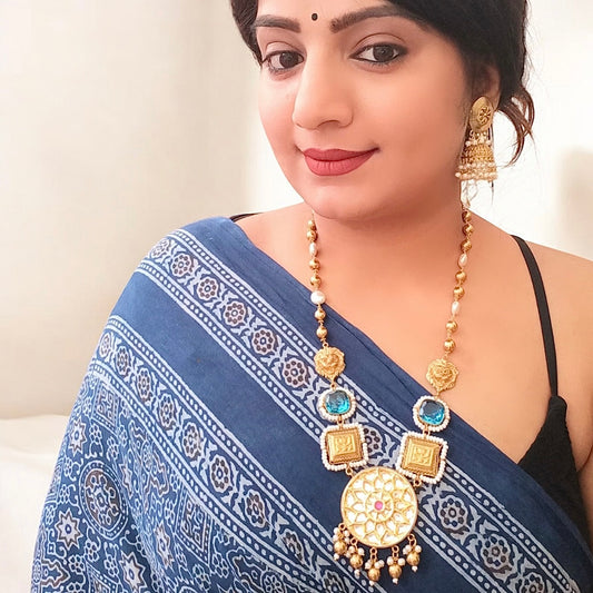 Model displaying a Premium designer Amrapali necklace set featuring gold-toned beads, doublet stones in teal and white, a statement circular pendant with intricate detailing and pink gemstone, paired with pearl drop earrings.