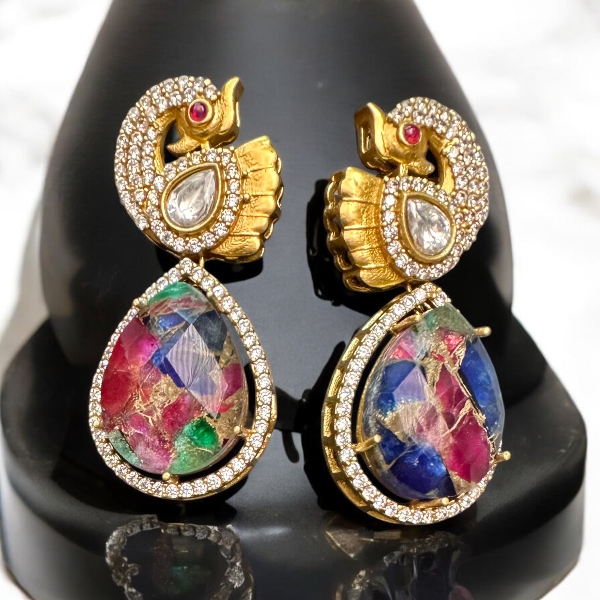Premium doublet multicolor stone earrings featuring intricate moissanite kundan work in a peacock-inspired design, displayed on a black bust against a soft background.