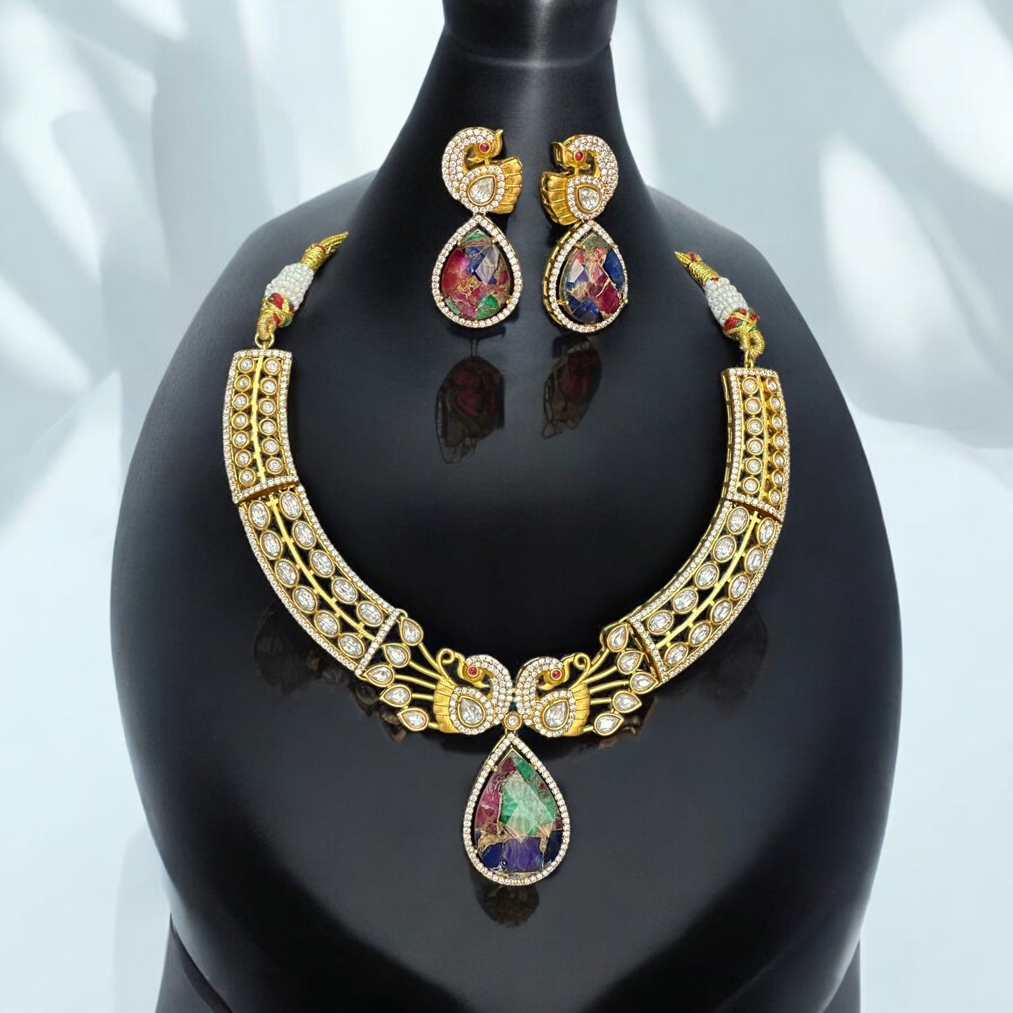 Premium doublet multicolor stone necklace featuring intricate moissanite kundan work in a peacock-inspired design, paired with matching earrings, displayed on a black bust against a soft background.