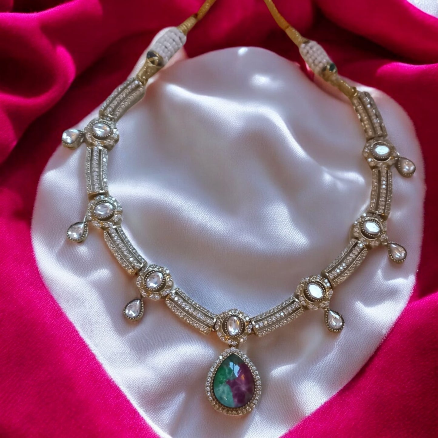 Premium moissanite necklace with green and ruby multi-colour doublet stones placed on a white and red satin fabric