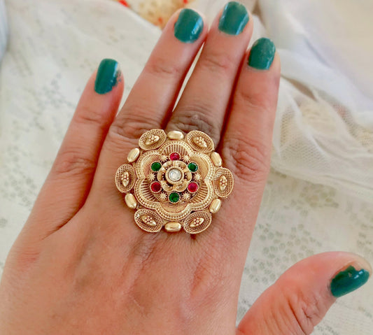 A woman's hand showcasing a Rajwadi Multicolor Golden Finger Ring with intricate floral design, gold-toned finish, and multicolor stone embellishments, exuding traditional festive elegance.