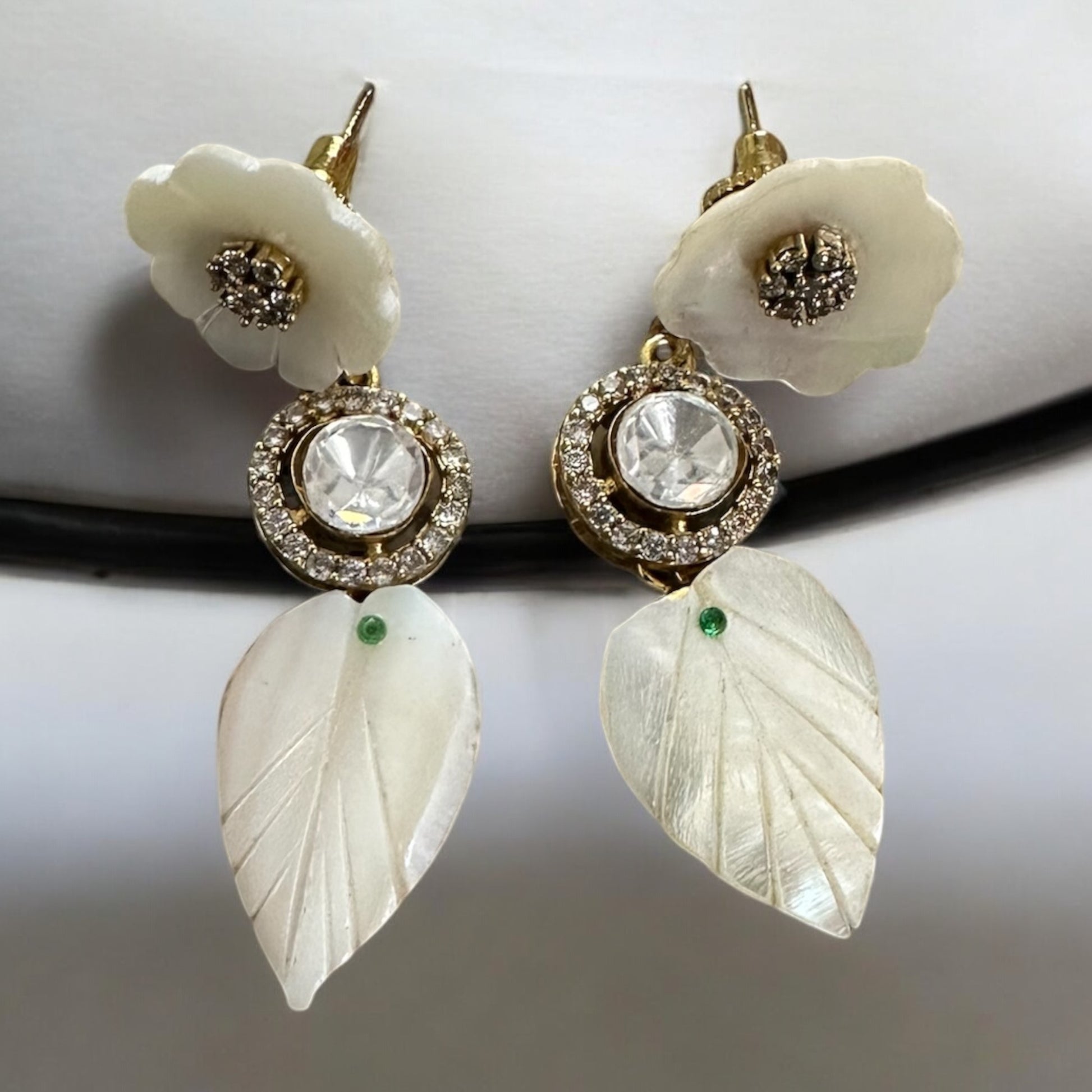 Real MOP_Mother Of Pearls_Moissanite Gold Plated Kundan Chokar earrings lying on a white colored jewellery display stand.