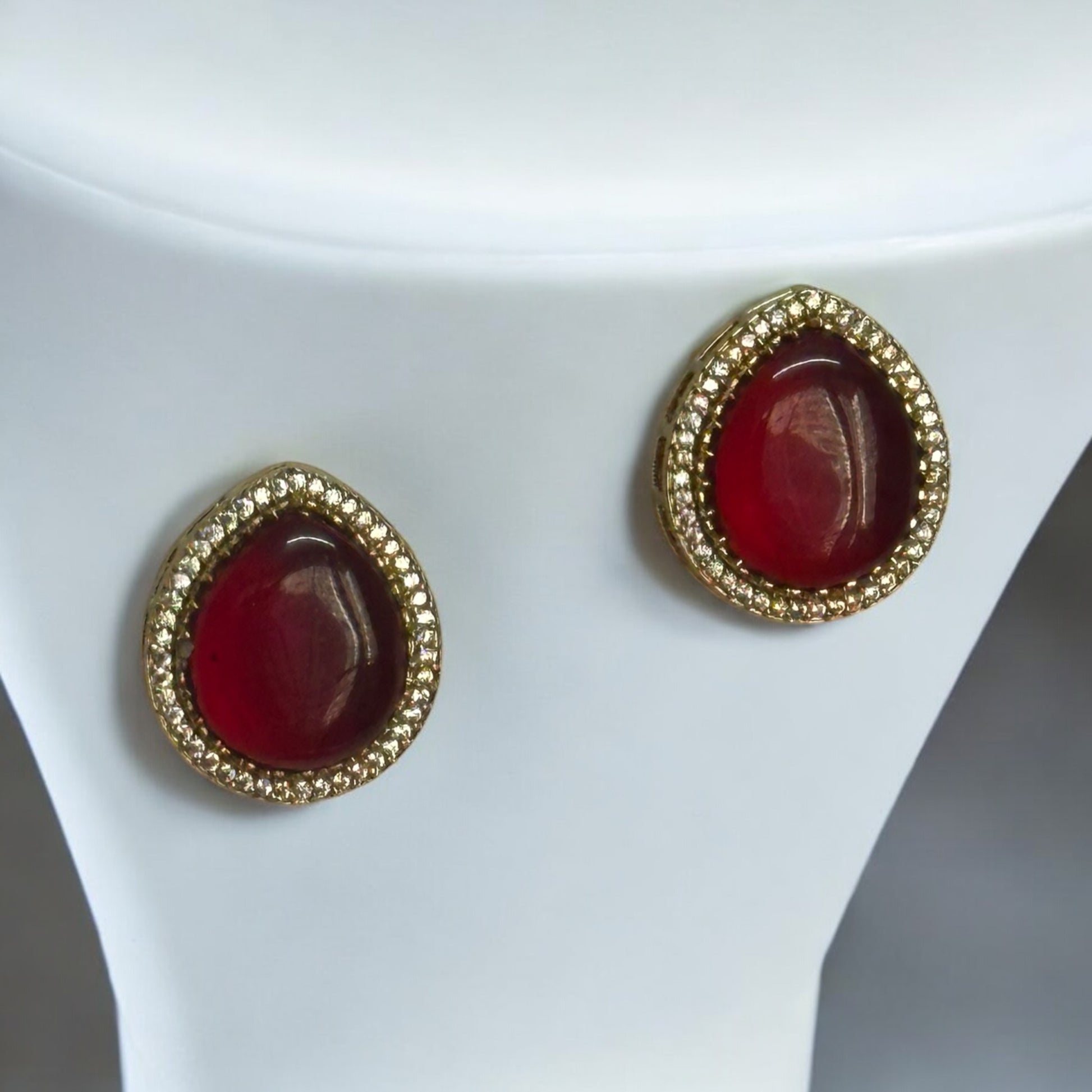 Red Monalisa Pendant Sets' Earrings with American Diamonds, featuring a bold centerpiece and are placed on a white coloured jewellery display stand.