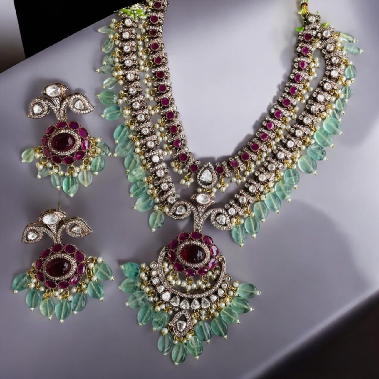 Elegant Royal Moissanite Polki Necklace Set Rani Haar featuring double-layered design with sparkling Moissanite, Polki stones, ruby accents, emerald-hued beads, and matching chandelier earrings. Perfect for weddings and festive occasions.