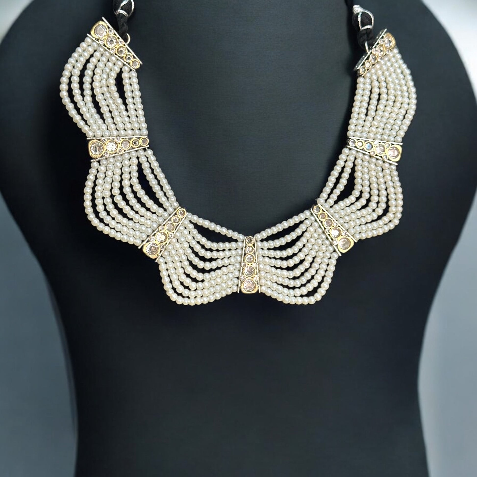 Royal Pearl Necklace featuring multiple layers of pearls with gold-tone accents, displayed on a black bust against a soft black backdrop.