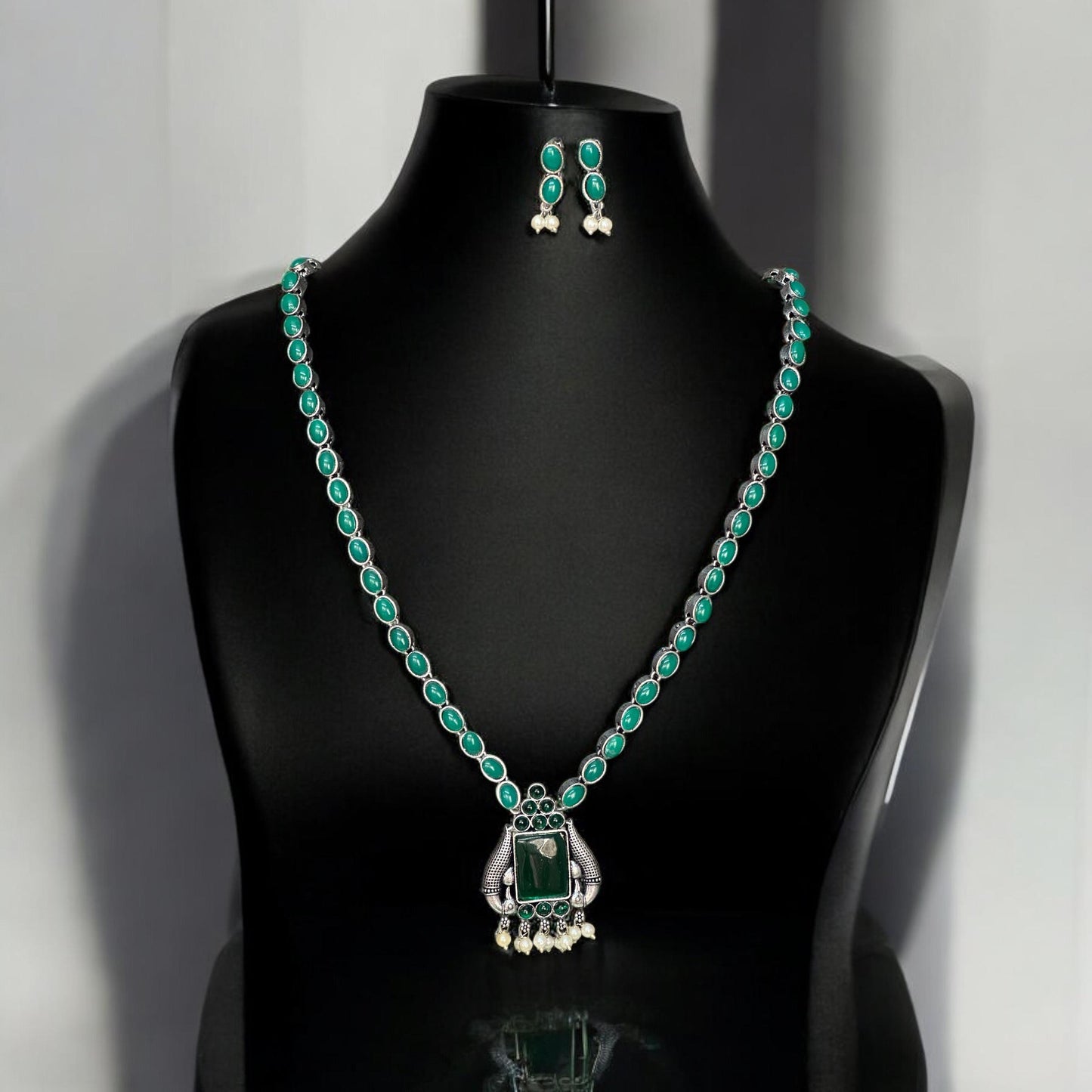 Close-up of silver look alike necklace with green gemstones and pearl detailing – Bella & Diva Indian traditional jewellery.
