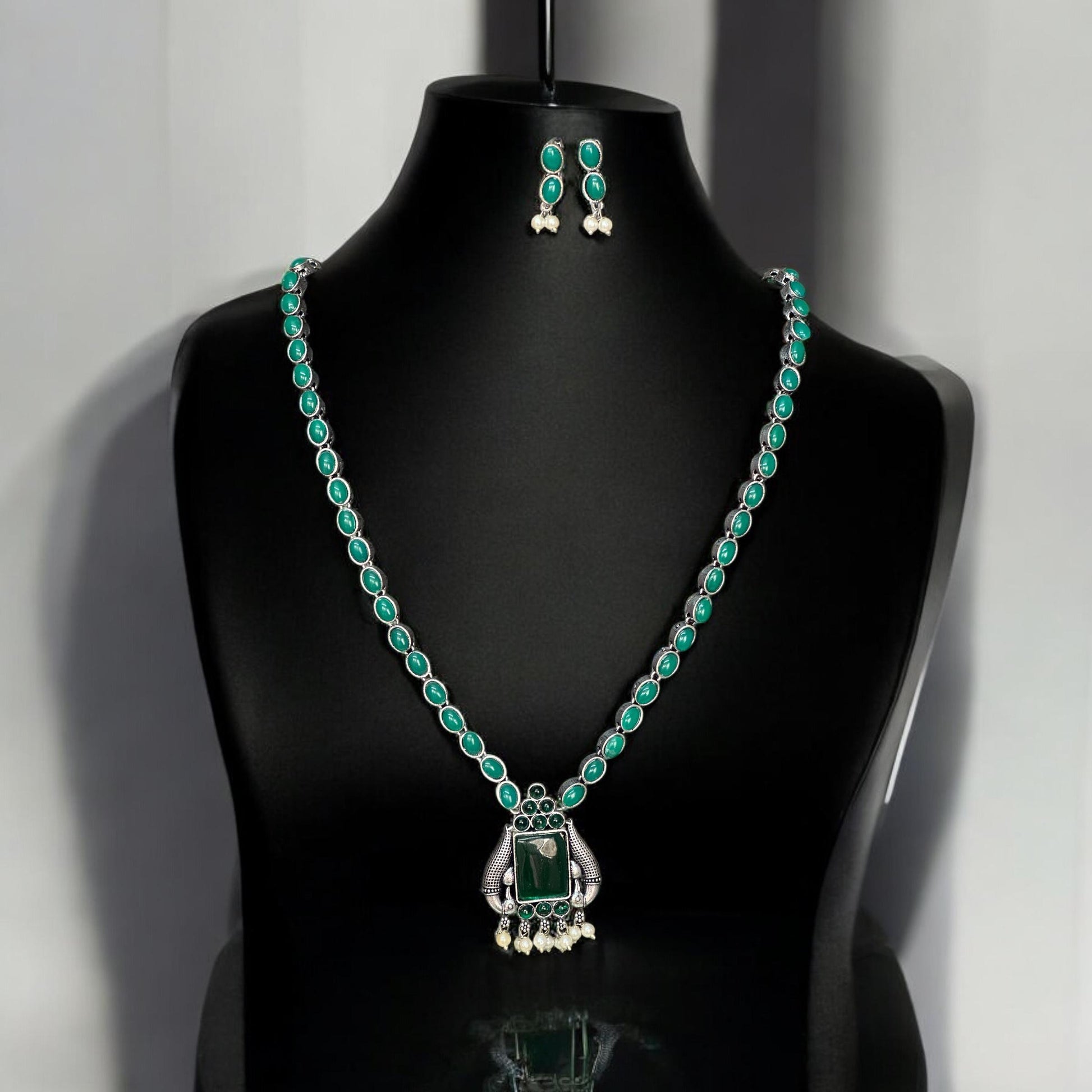 Close-up of silver look alike necklace with green gemstones and pearl detailing – Bella & Diva Indian traditional jewellery.