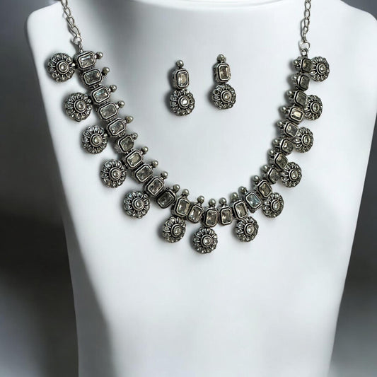 Silver look alike necklace set with white diamond stones, oxidised silver floral design, displayed on white mannequin – ethnic jewellery for women UK.