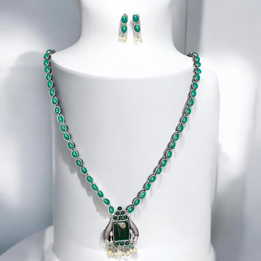 Silver look alike green stone necklace set displayed on a white stand – Indian designer jewellery by Bella & Diva.
