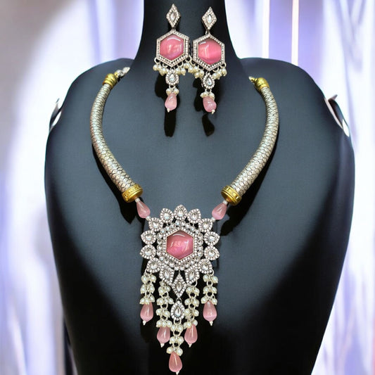 Silver Look-Alike Hasli Necklace Set adorned with pink Monalisa stones and intricate diamond work, paired with matching earrings. The set is displayed against a soft lilac drape background on a black bust.