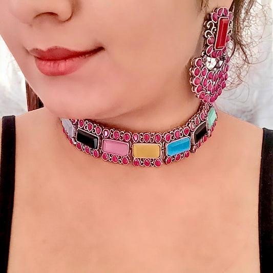 A Model wearing and displaying a Silver Replica Multicolour Choker Necklace featuring vibrant gemstones in pink, blue, yellow, and more, paired with matching Chandbali-style earrings.