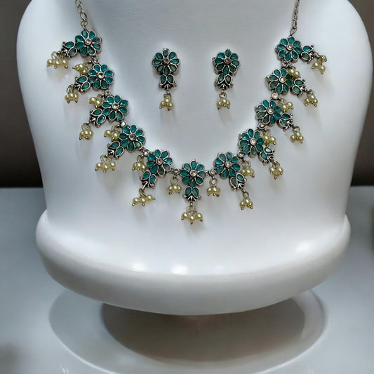 Silver Replica Necklace Set in Sky Blue featuring delicate floral motifs adorned with pearl accents, paired with matching earrings, displayed on a white mannequin stand.