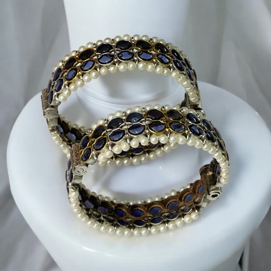 Silver Replica Purple Bangles adorned with white pearls and intricate design, perfect for elegant occasions. Standing on a white jewellery display stand.