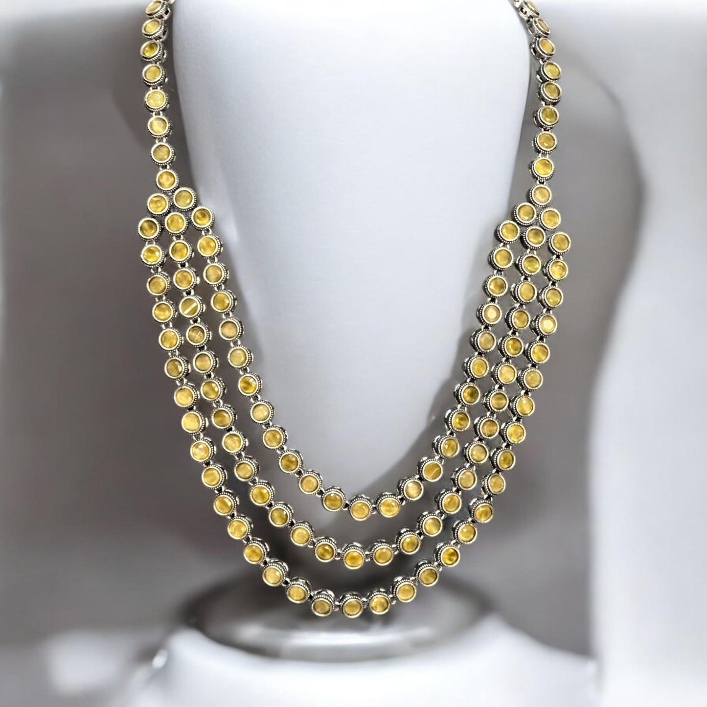Silver replica three-layer necklace set with yellow stones displayed on white mannequin bust