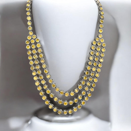 Silver replica three-layer necklace set with yellow stones displayed on white mannequin bust