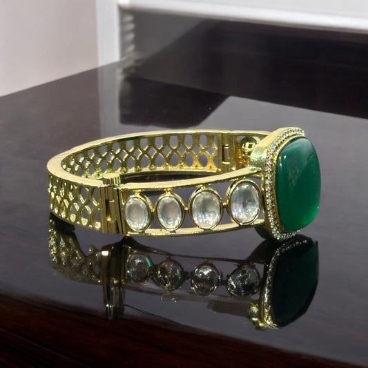 Single Kada With Green Doublet Stone Polki Kundan Bracelet placed on a dark shiny tile.