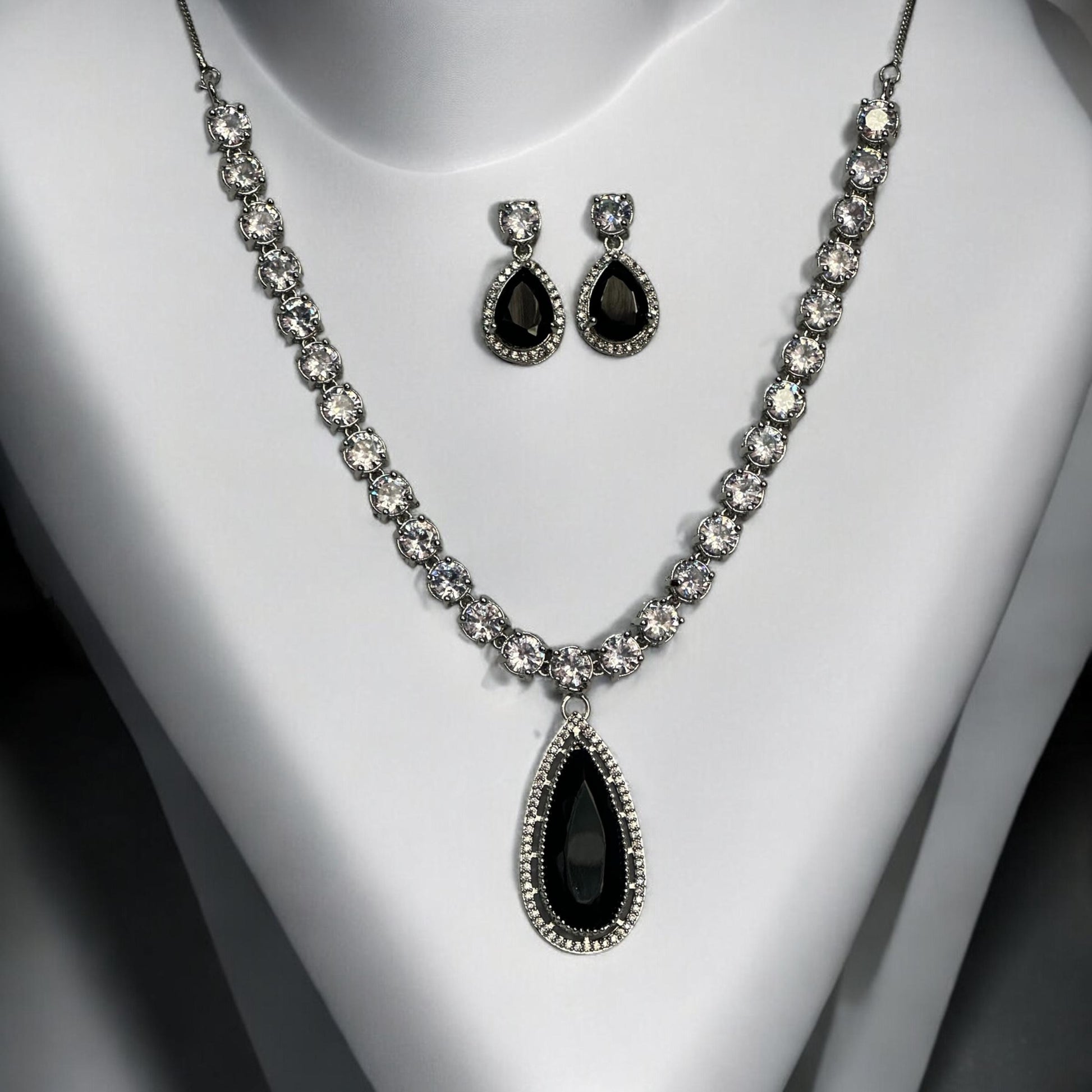 Statement silver black and white diamond necklace set with teardrop pendant and matching earrings displayed on white bust stand