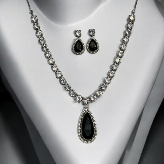 Statement silver black and white diamond necklace set with teardrop pendant and matching earrings displayed on white bust stand