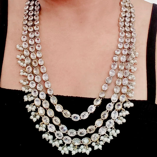 A model displaying a Statement silver replica necklace set featuring three layers of dazzling white stones with matching jhumka earrings, displayed on a black mannequin with intricate detailing.