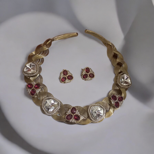 Statement hasli necklace with Apala polish in gold and ruby tones, featuring moissanite stones and matching earrings, laid against a neutral backdrop.