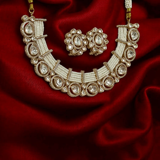 Tyani Kundan pearl necklace set with large matching studs displayed on red silk fabric – Bella & Diva