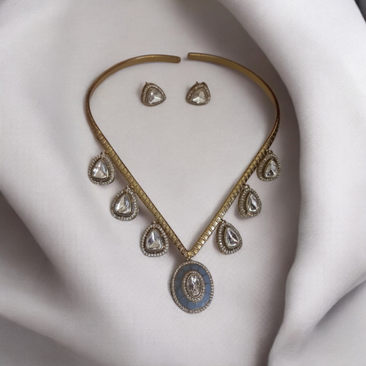 Handmade V-shaped Apala polish hasli necklace with moissanite stones and grey accents, paired with matching earrings, displayed on a white fabric.