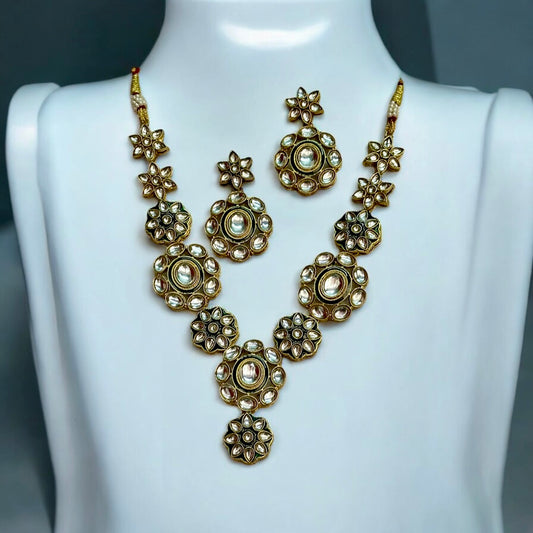 Elegant Kundan necklace set featuring intricate floral designs in green and gold tones, paired with matching earrings, placed on a white coloured jewellery display stand. These are perfect for traditional and festive occasions. Now available on bellandiva.com.